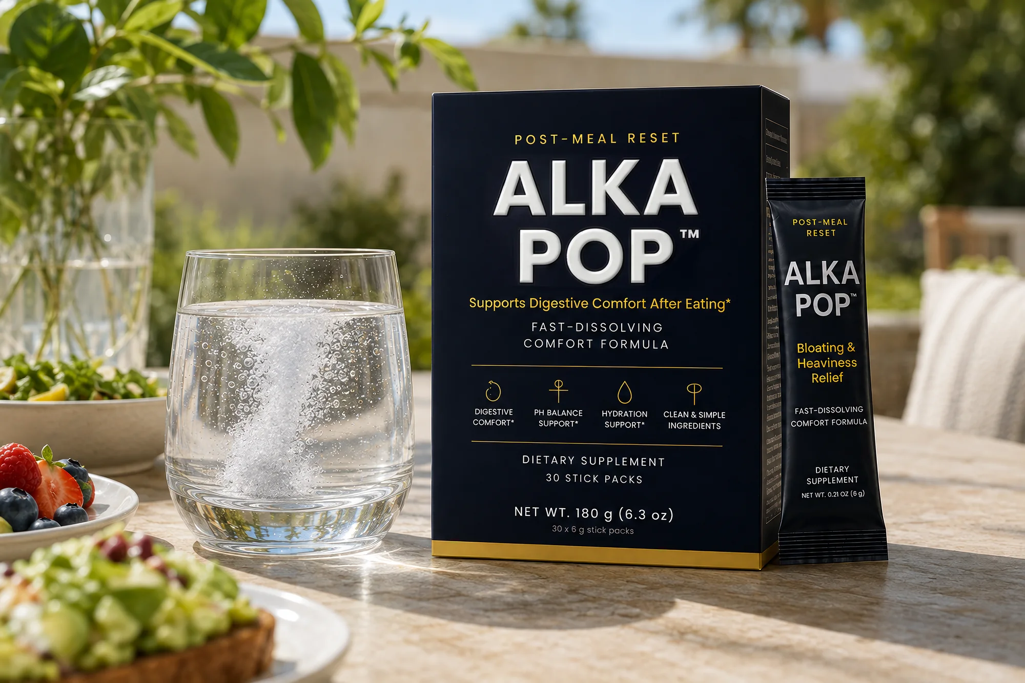 A hand stirring an ALKA POP stick pack into a glass of water on a candlelit table after dinner